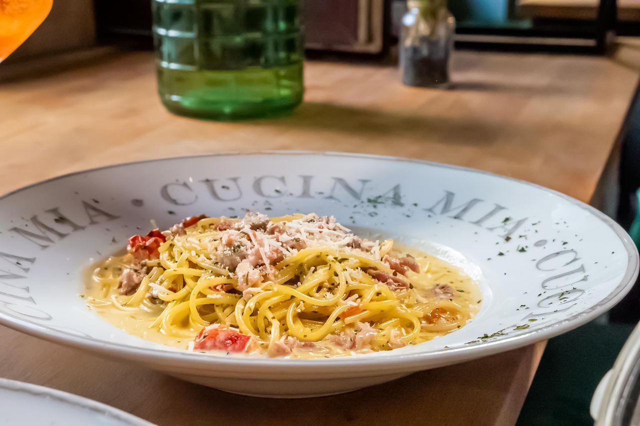 Pastagericht mit heller Sauce und geriebenem Käse in einem tiefen Teller